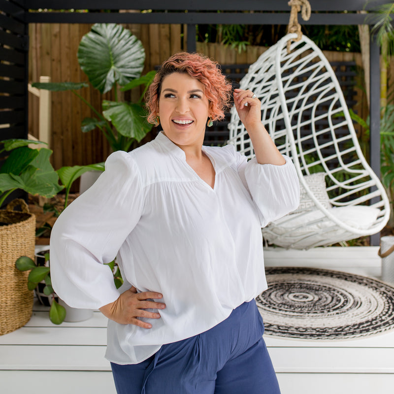 Jo is wearing Felicity technical billow blouse in white tucked into Maddy technical crop pant in steel blue.