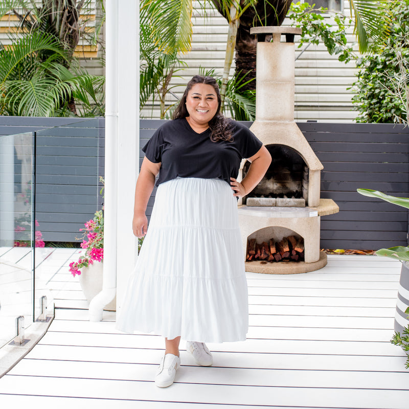 Charity is wearing our Alexa tee in black tucked into Sophie technical maxi skirt in white with white sneakers