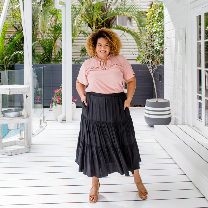 Asinate is wearing our Kim blouse in peach tucked into Sophie Maxi skirt in black and tan sandals
