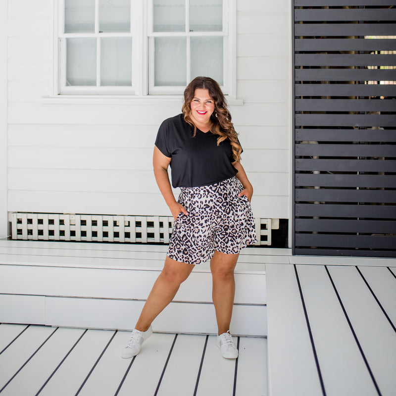 Stacey wearing our Alexa tee in black tucked into our Gillian animal print shorts with white sneakers. 