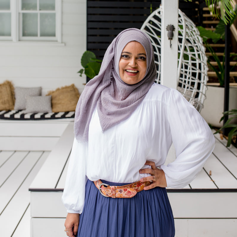 Faaiza is wearing our Felicity technical billow blouse in white tucked into Sophie maxi skirt in steel blue with floral belt and grey Hijab.