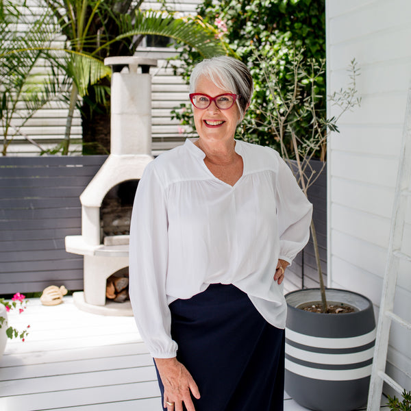 Jan wearing our Felicity technical billow blouse in white tucked into Fiona  scuba pencil skirt in navy. She's also wearing red glasses.