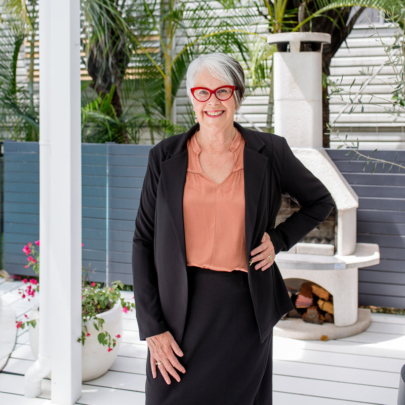 Jan wearing Helen blazer in black on top our Gwendolyn Satin billow sleeve blouse in toffee tucked into Fiona scuba pencil skirt in black . She's also wearing red glasses.