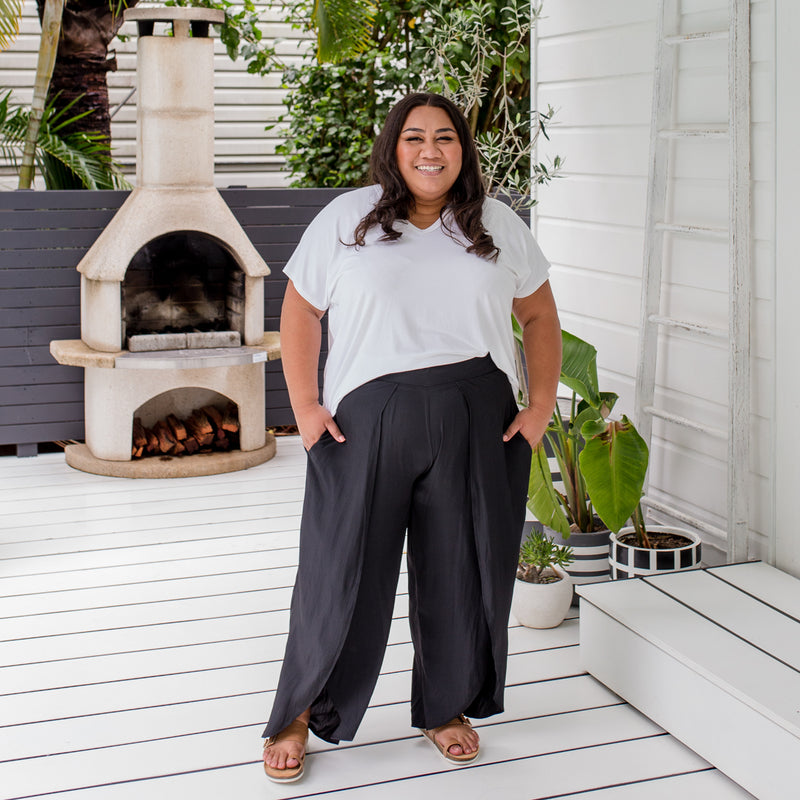 Charity is wearing our Alexa tee in white tucked into Maria technical split pants in black and tan slides