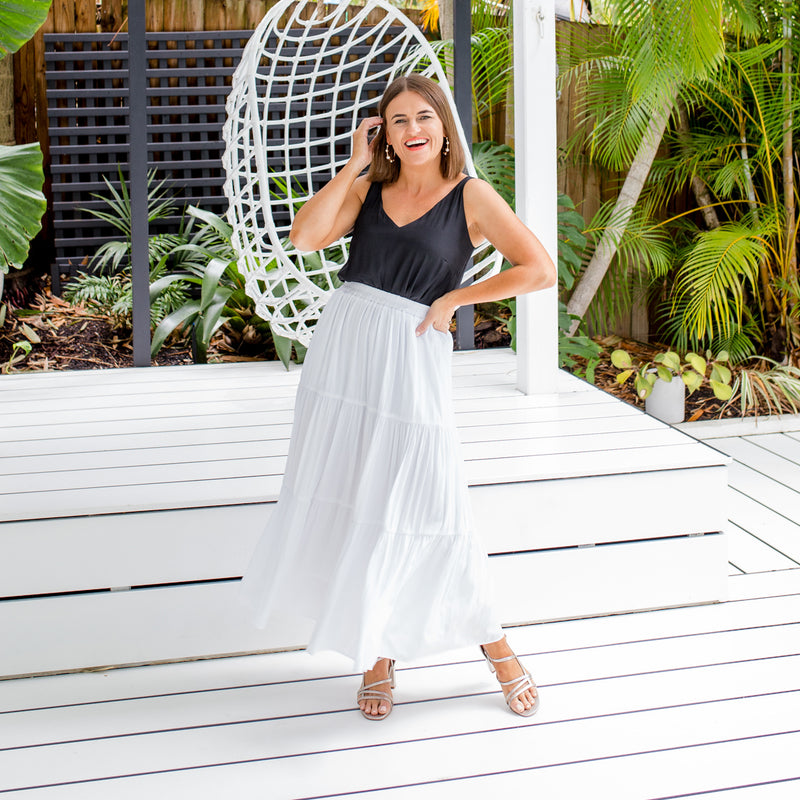 Jasmine is wearing our Rachael technical cami in black tucked into Sophie maxi skirt in white and silver heels