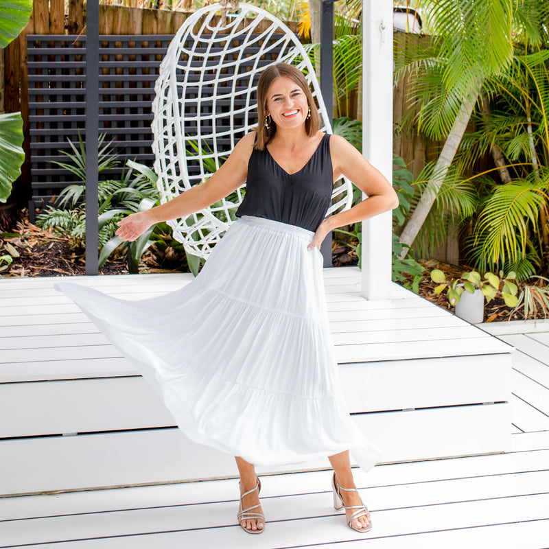Jasmine is wearing our Rachael technical cami in black tucked into Sophie maxi skirt in white with silver sandals