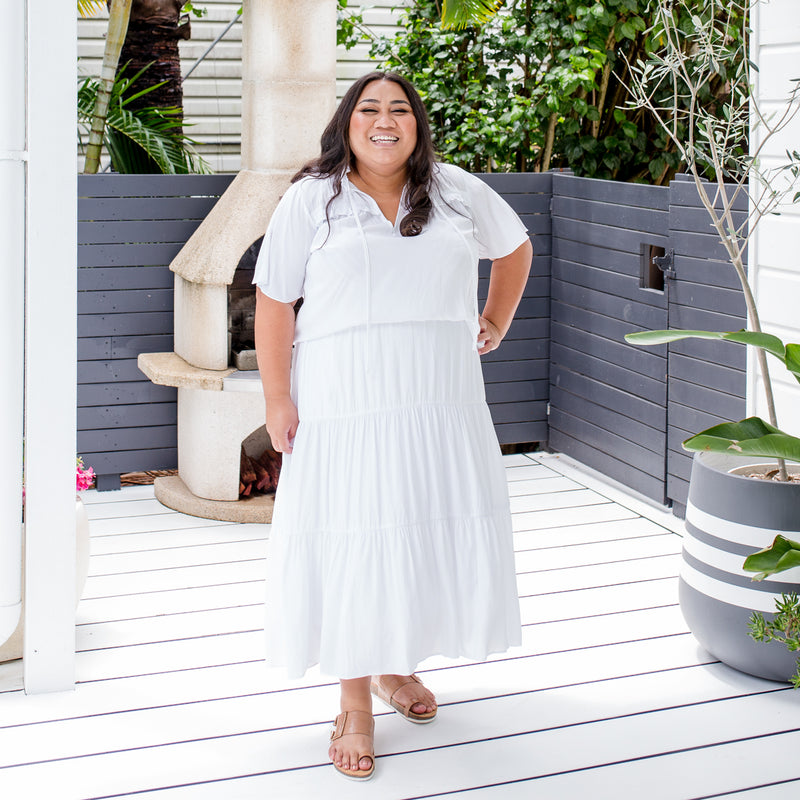 Charity is wearing our Kim technical blouse in white tucked into Sophie Maxi skirt in white and tan slides