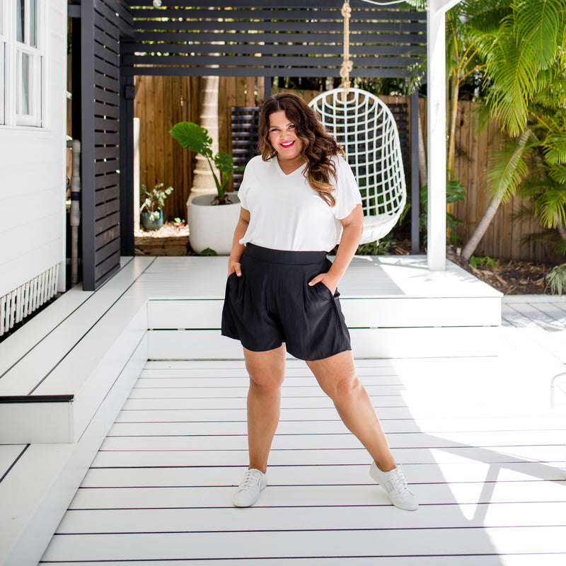 Stacey is wearing white Alexa tee tucked into Bec shorts in black and white sneakers