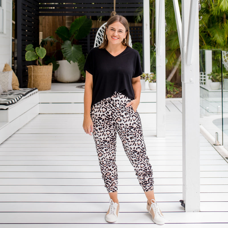 Jasmine wearing our Alexa tee in black tucked into our Leanne pants in black with white sneakers